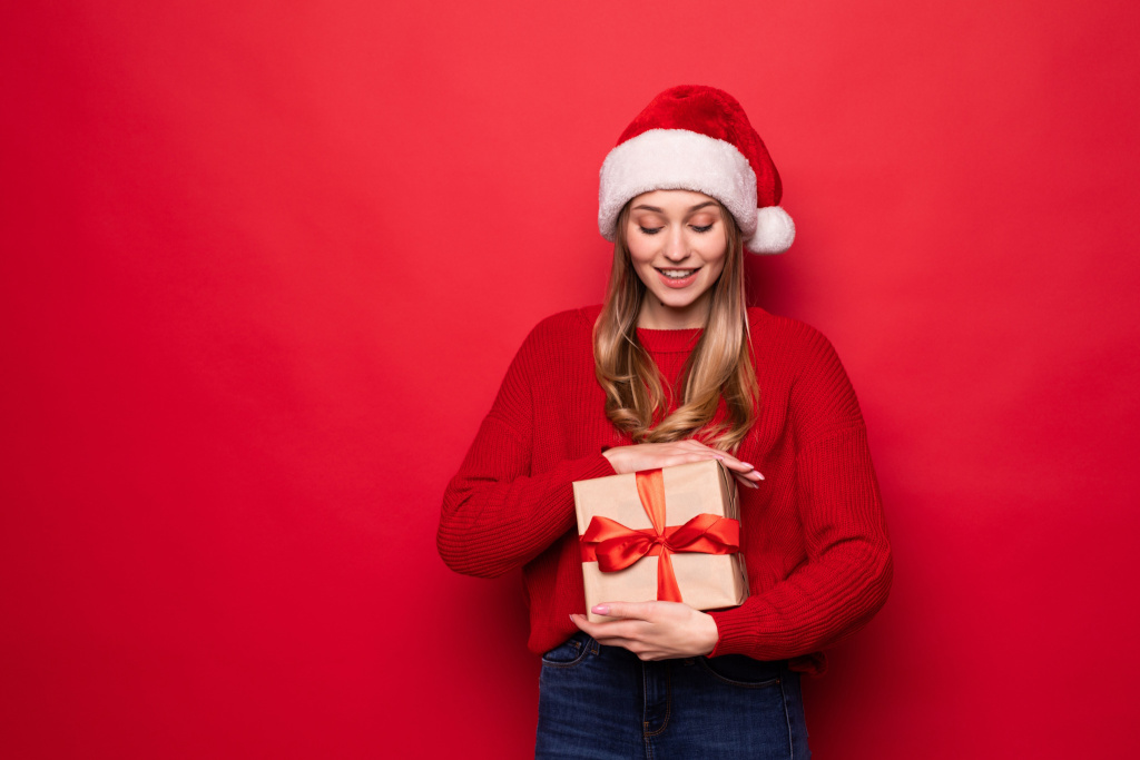 beautiful-woman-santa-hat-holding-giftbox-hands-isolated-red-wall.jpg